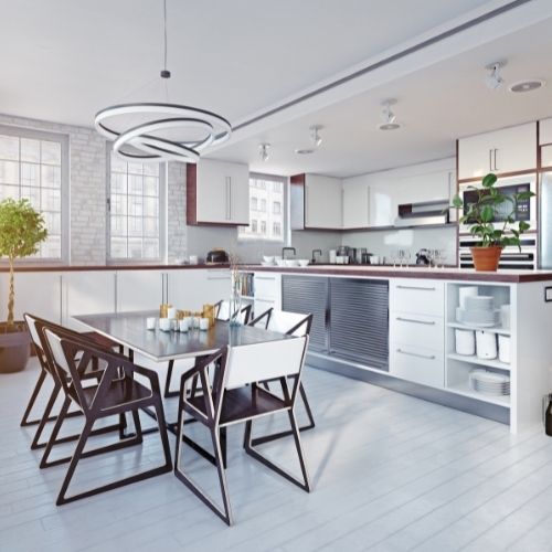 A bright and modern kitchen featuring white cabinets and an artsy chandelier above a large kitchen table.