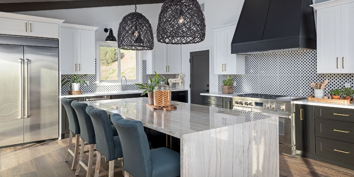 A modern kitchen with a large island and hanging pendant lights.