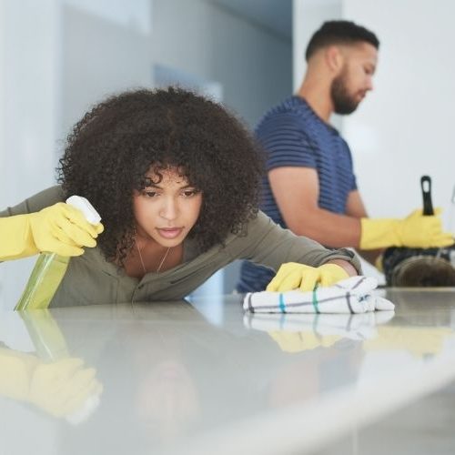 Two professional house cleaners deep cleaning a kitchen.